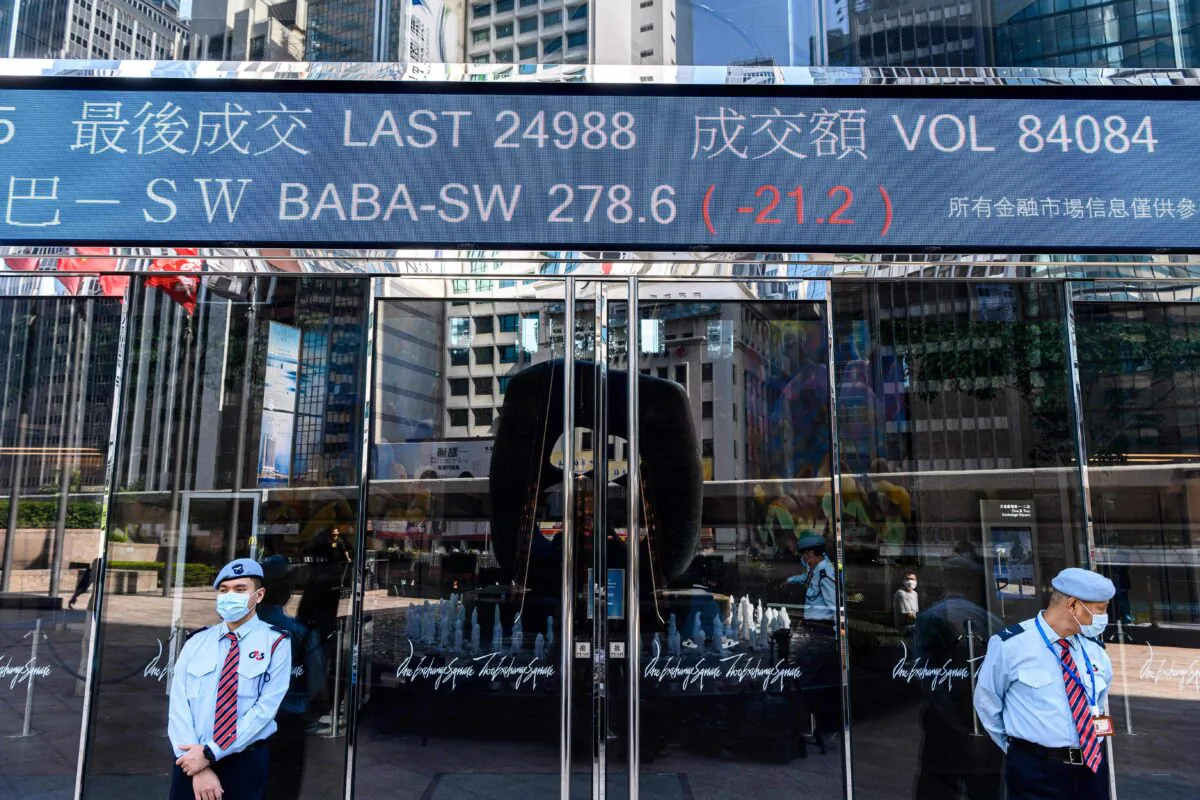 Stock activity of the Alibaba Group Holding Ltd (BABA-SW) is displayed above security guards standing outside the Exchange Square towers in Hong Kong on Nov. 4, 2020. (Anthony Wallace/AFP via Getty Images)