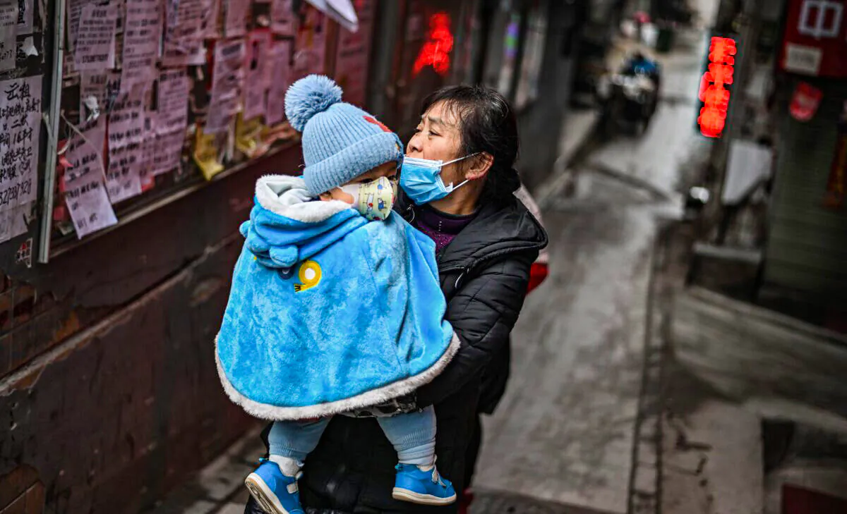 A woman wearing a face mask as a preventive measure against COVID-19 walks on a path carrying a baby in her arms in Wuhan, China's central Hubei province, on Jan. 22, 2021. (Hector Retamal/AFP via Getty Images)