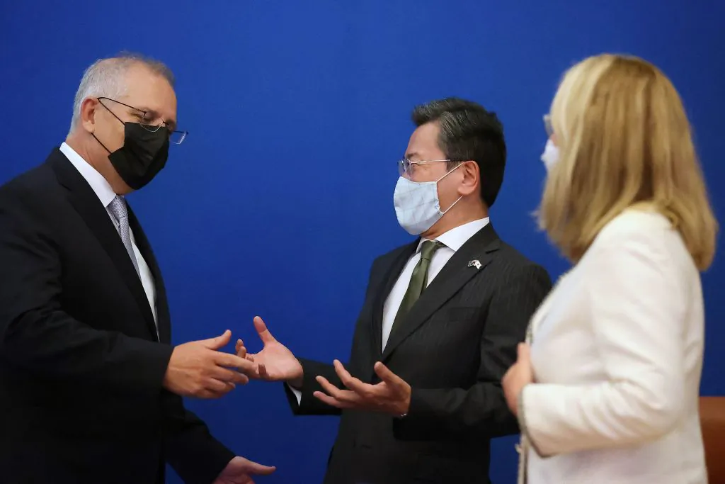 Australian Prime Minister Scott Morrison (L) talks with Japan's Ambassador to Australia Shingo Yamagami (C) after a virtual summit with Japanese Prime Minister Kishida Fumio in Canberra on January 6, 2022, to mark the opening of a new chapter of defence and security cooperation between the two countries, with the signing of a Reciprocal Access Agreement. (Photo by -/AFP via Getty Images)