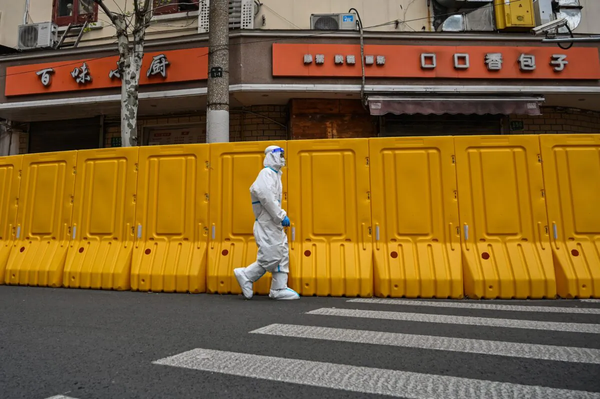 A worker walks next to barriers that separate the street from buildings in a neighborhood in lockdown in Jing'an district, in Shanghai on March 30, 2022. (Hector Retamal/AFP via Getty Images)