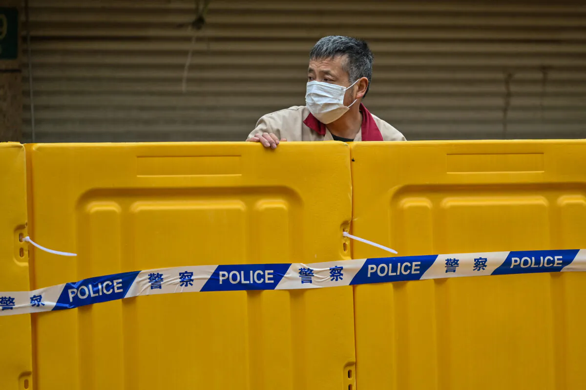 A man stands behind barriers during lockdown as a measure against COVID-19 in Jing'an district, Shanghai, on March 31, 2022. (Hector Retamal/AFP via Getty Images)
