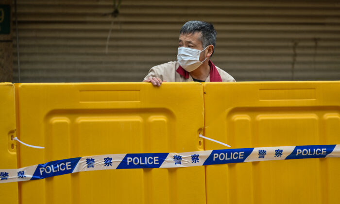 A man stands behind barriers during lockdown as a measure against COVID-19 in Jing'an district, Shanghai, on March 31, 2022. (Hector Retamal/AFP via Getty Images)