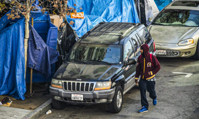 A man walks past a homeless encampment in Los Angeles on Jan 6, 2022. (John Fredricks/The Epoch Times)