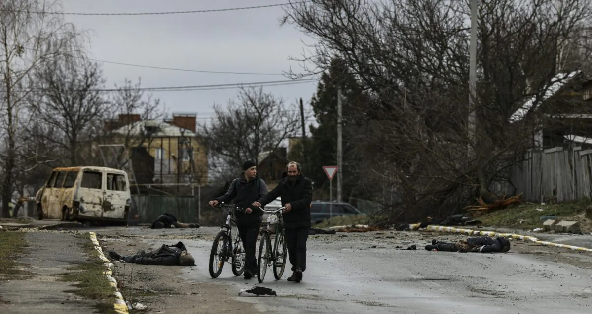 Two person push their bicycle as they cross a street in Bucha, northwest of Kyiv, Ukraine, on April 2, 2022. (Ronaldo Schemidt/AFP via Getty Images)