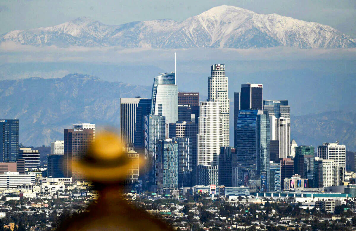 A person looks toward snow-topped mountains behind the Los Angeles downtown skyline following heavy rains, as seen from the Kenneth Hahn State Recreation Area in Los Angeles on Dec. 15, 2021. (Patrick T. Fallon/AFP via Getty Images)