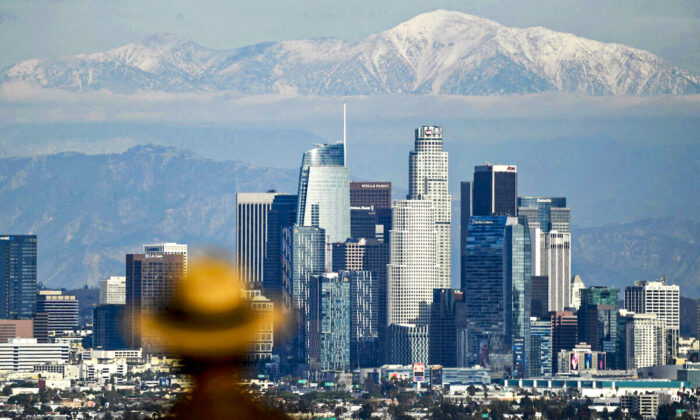 A person looks toward snow-topped mountains behind the Los Angeles downtown skyline following heavy rains, as seen from the Kenneth Hahn State Recreation Area in Los Angeles on Dec. 15, 2021. (Patrick T. Fallon/AFP via Getty Images)