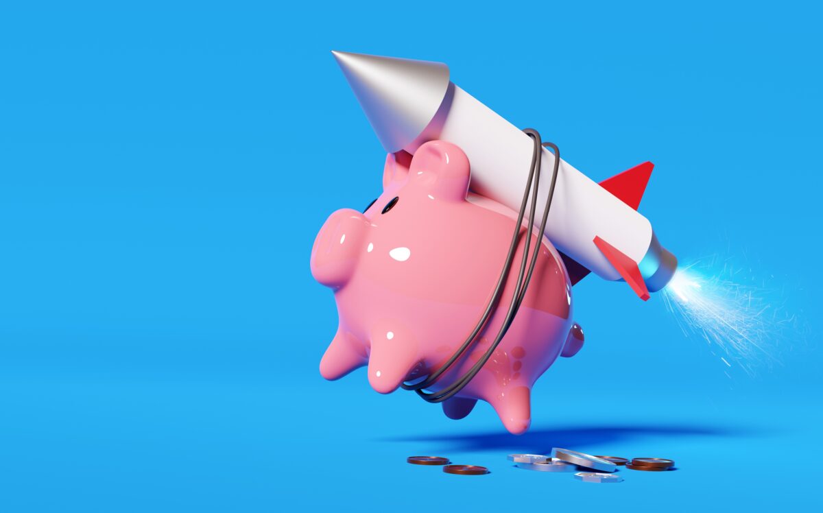 A pink piggy bank strapped to a rocket launching it into the air. (Shutterstock)