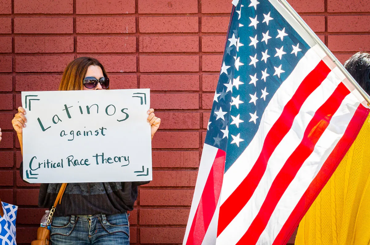 A woman holds a sign against critical race theory in Los Alamitos, Calif., on May 11, 2021. (John Fredricks/The Epoch Times)