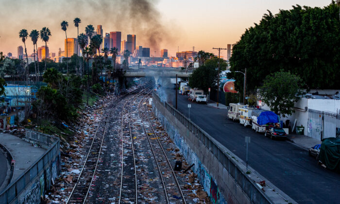 Smoke from a fire at a homeless encampment is seen near railroad tracks littered with boxes left behind from stolen items in Los Angeles on Jan. 2, 2022. (John Fredricks/The Epoch Times)