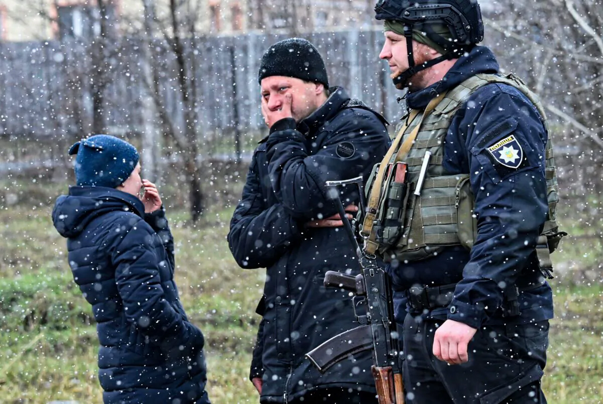 People react as they gather near a grave site in the town of Bucha, just northwest of the Ukrainian capital Kyiv, on April 3, 2022. (Sergei Supinsky/AFP via Getty Images)