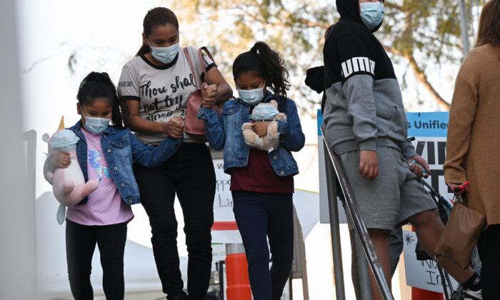 A woman and girls leave a COVID-19 testing site in Los Angeles, Calif., on Jan. 5, 2022. (Robyn Beck/AFP via Getty Images)