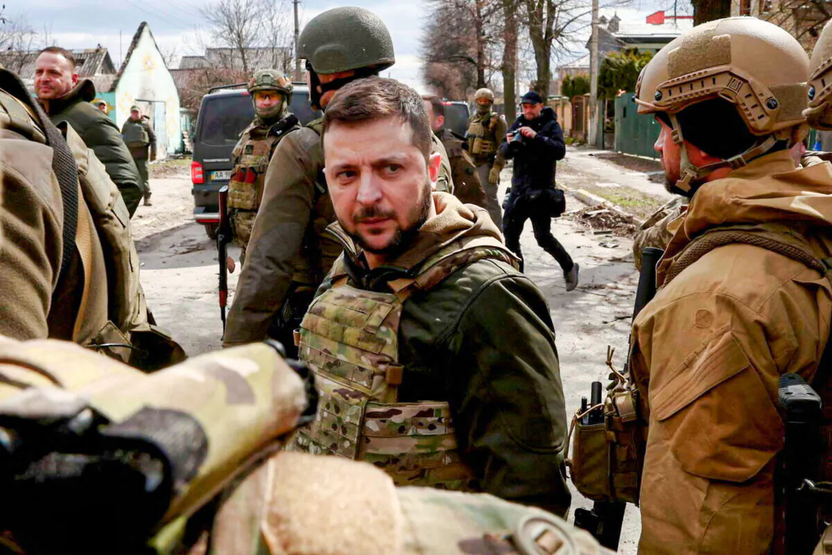 Ukraine's President Volodymyr Zelenskyy looks on as he's surrounded by Ukrainian servicemen in Bucha, outside Kyiv, Ukraine, on April 4, (2022. REUTERS/Marko Djurica)