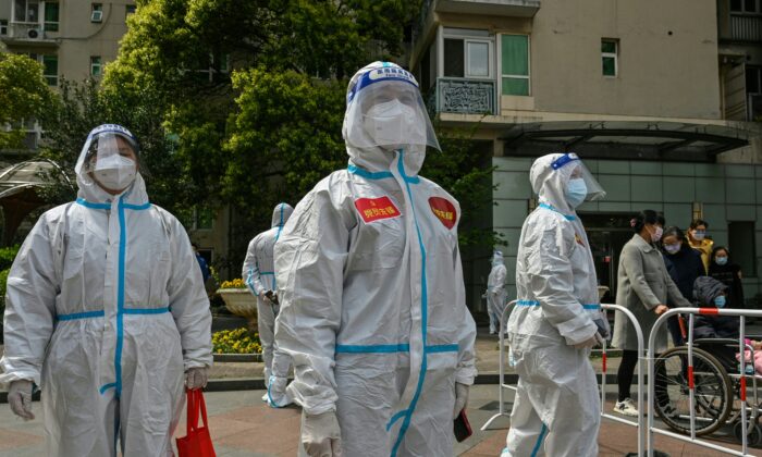 2022 年 4 月 1 日，在上海静安区大流行封锁的第二阶段，工人们和志愿者在一个大院里观看居民接受 Covid-19 冠状病毒检测。（Hector Retamal/法新社通过 Getty Images）