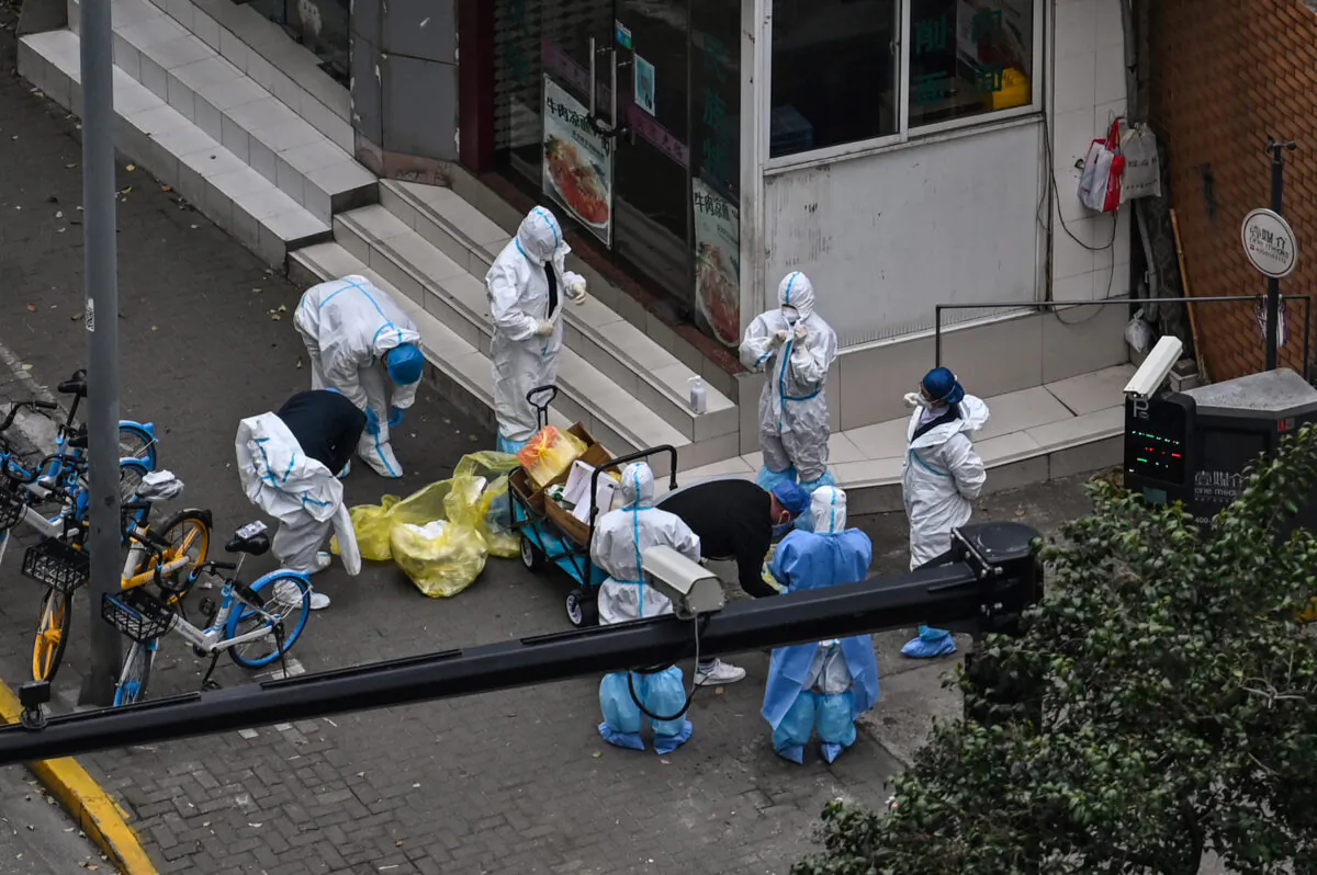 Workers take off their protective gear next to the entrance of a neighborhood during the second stage of a pandemic lockdown in Jing'an district in Shanghai on April 5, 2022. (Hector Retamal/AFP via Getty Images)