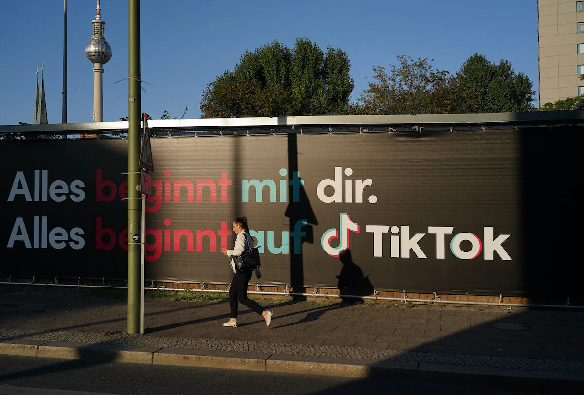 A young woman holding a smartphone walks past an advertisement for social media company TikTok in Berlin, Germany, on Sept. 21, 2020. (Sean Gallup/Getty Images)