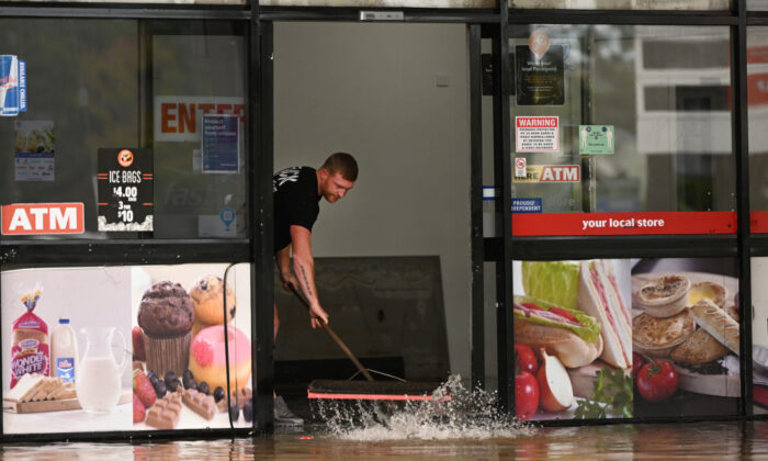 A man pushes water out of a flood-affected business in Lismore, Australia, on March 31, 2022. (Dan Peled/Getty Images)