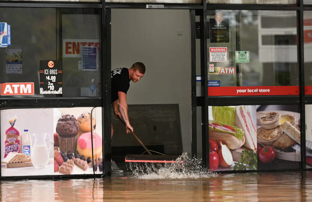 A man pushes water out of a flood-affected business in Lismore, Australia, on March 31, 2022. (Dan Peled/Getty Images)
