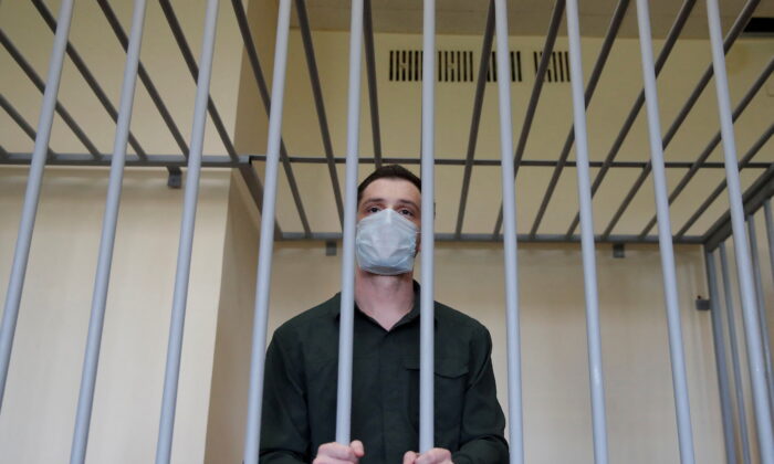 Former U.S. Marine Trevor Reed, who was detained in 2019 and accused of assaulting police officers, stands inside a defendants' cage during a court hearing in Moscow, on July 30, 2020. (Maxim Shemetov/Reuters)