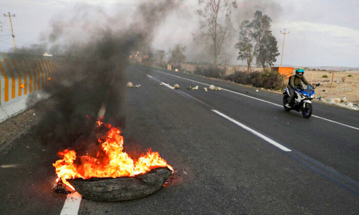 A burning tire serves as part of a blockade of a highway to Lima during a national transportation strike in Ica, Peru, on April 4, 2022. (Sebastian Castaneda/Reuters)