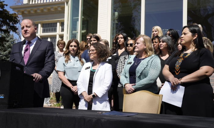 Colorado Governor Jared Polis speaks before signing into law the Reproductive Health Equity Act during a ceremony outside the governor's mansion in Denver, Colo., on April 4, 2022. The bill's sponsors, Sen. Julie Gonzalez, far right, Rep. Meg Froelich, center, and House majority leader Daneya Esgar, look on with guests and other lawmakers at the signing. (David Zalubowski/AP Photo)