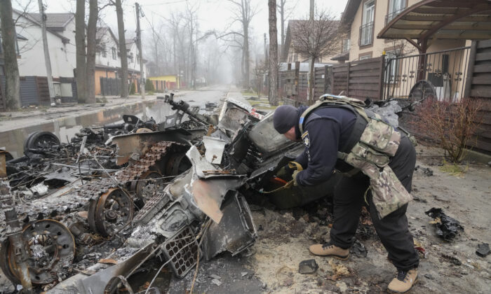 A Ukrainian soldier checks a destroyed Russian tank, in Irpin close to Kyiv, Ukraine, on April 1, 2022. (AP Photo/Efrem Lukatsky)