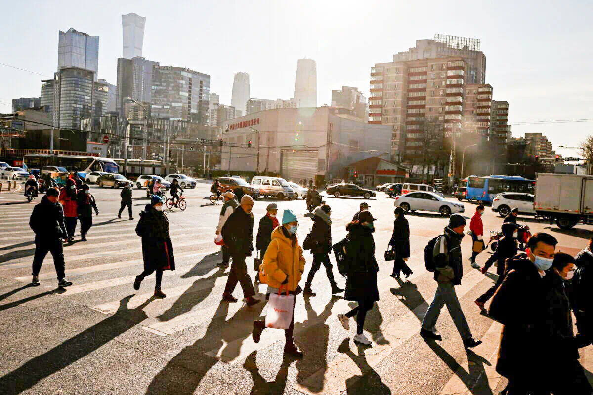 People cross a street during morning rush hour in front of the skyline of the central business district (CBD) in Beijing, on Dec. 15, 2020. (Thomas Peter/Reuters)