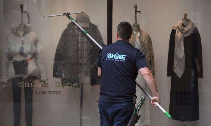 2021 年 5 月 11 日，一名窗户清洁工在澳大利亚墨尔本墨尔本中央商务区的一家店面工作。（威廉·韦斯特/法新社通过 Getty Images）