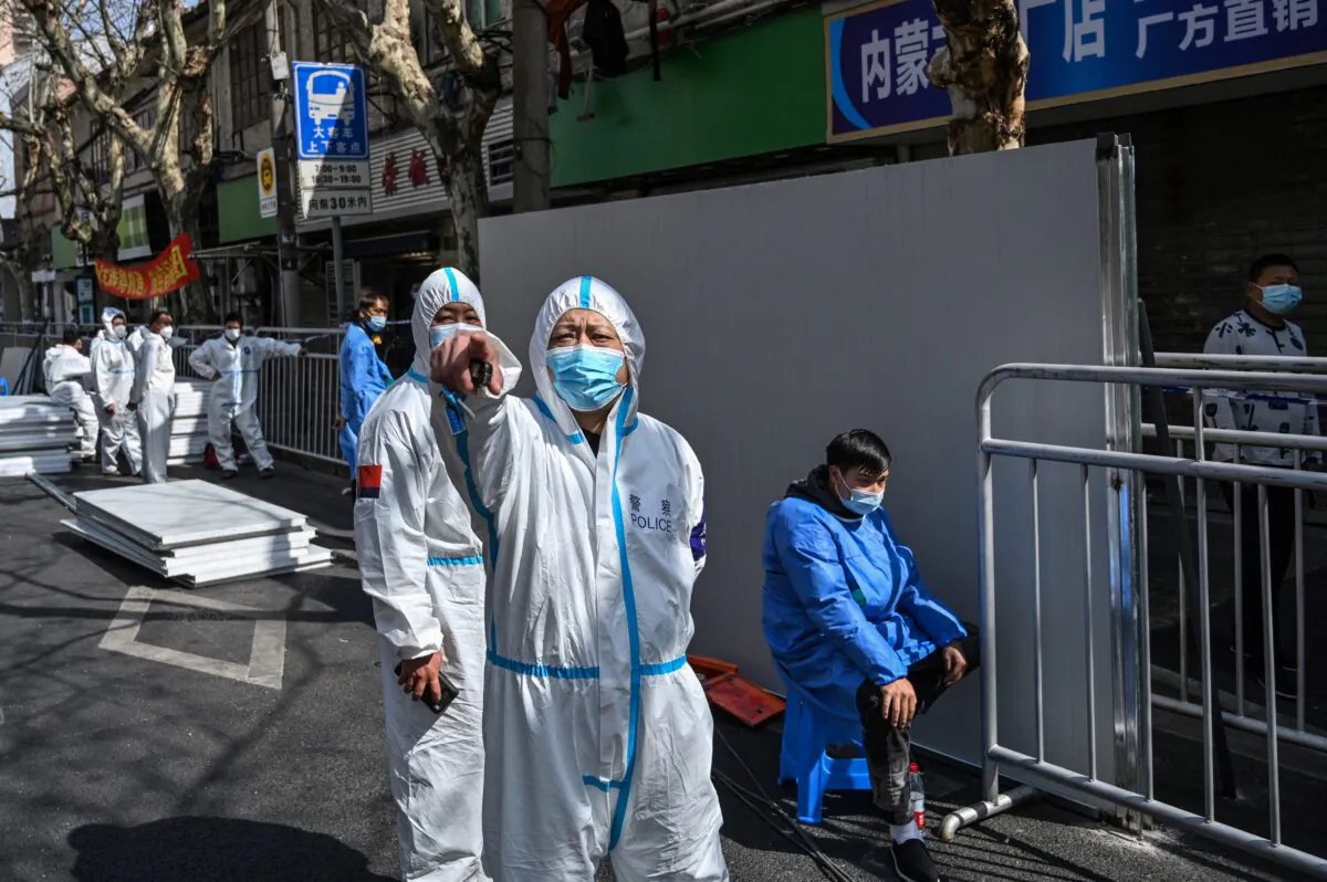A policeman (C) wearing protective clothing reacts in an area where barriers are being placed to close off streets around a locked-down neighborhood in Shanghai on March 15, 2022. (Hector Retamal/AFP via Getty Images)