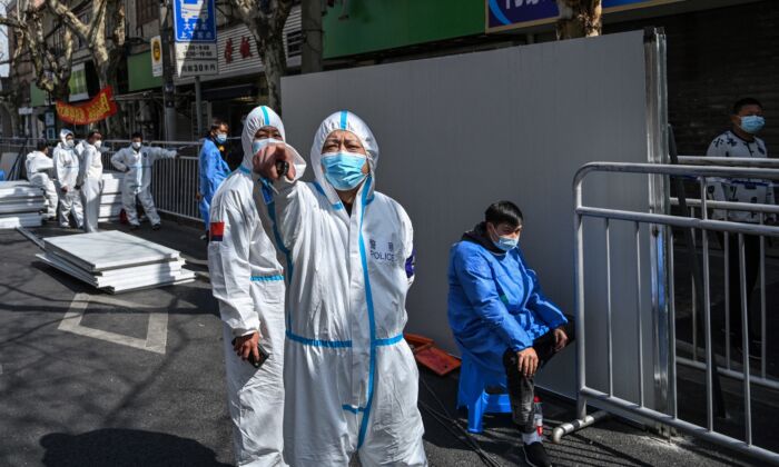 A policeman (C) wearing protective clothing reacts in an area where barriers are being placed to close off streets around a locked-down neighborhood in Shanghai on March 15, 2022. (Hector Retamal/AFP via Getty Images)