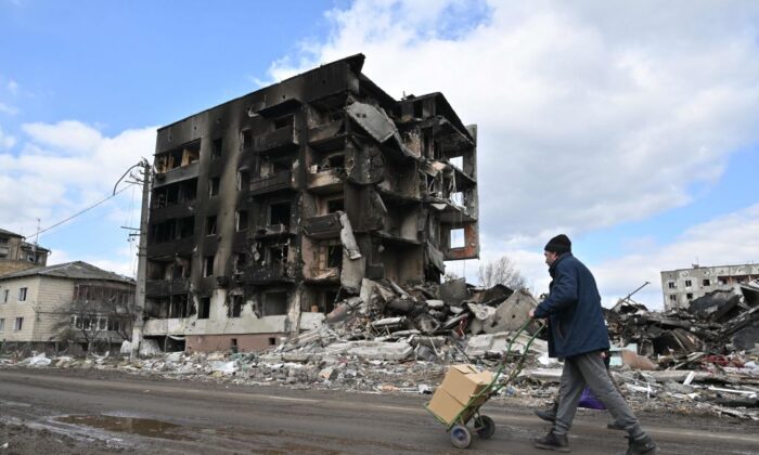 People walk past destroyed buildings in the town of Borodianka, northwest of Kyiv, on April 4, 2022. (Photo by Sergein Supinsky/AFP via Getty Images)