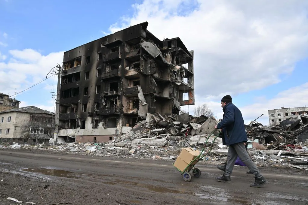 People walk past destroyed buildings in the town of Borodianka, northwest of Kyiv, on April 4, 2022. (Photo by Sergein Supinsky/AFP via Getty Images)