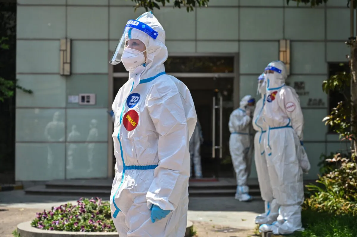 Workers and volunteers stand in a compound where residents are being tested for COVID-19 during the second stage of a pandemic lockdown in Jing'an district in Shanghai, China, on April 6, 2022. (Hector Retamal/AFP via Getty Images)
