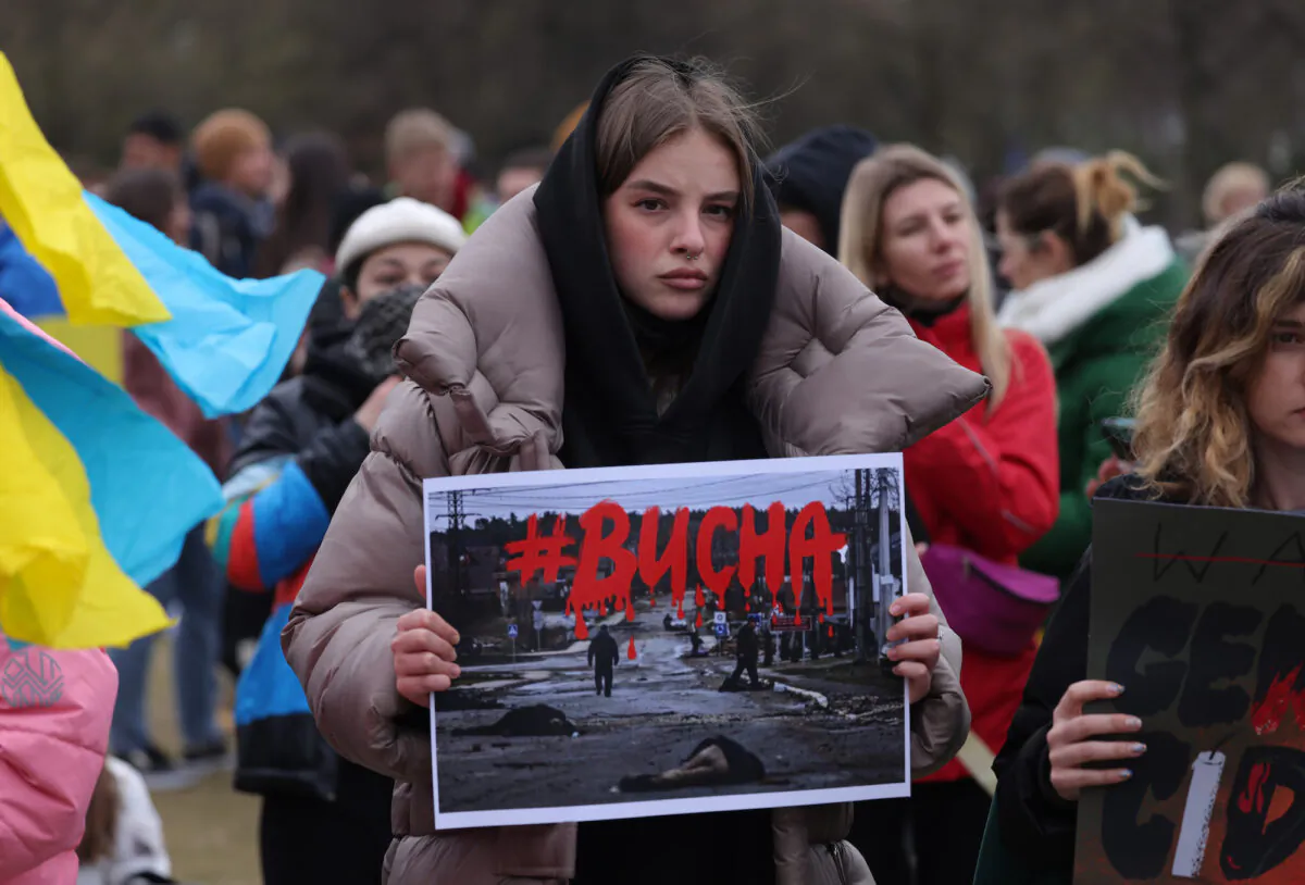 A protester holds up a photograph showing murdered civilians of the Ukrainian town of Bucha near Kyiv during a demonstration against the Russian military invasion of Ukraine in Berlin, Germany, on April 6, 2022. (Sean Gallup/Getty Images)