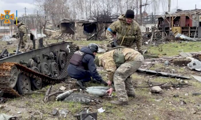 State Emergency Service members collect ordnance after Russia's withdrawal from the area, in Bucha, Ukraine, in this still image taken from video uploaded to a social media website on April 4, 2022. (State Emergency Service in Kyiv Oblast/Handout via Reuters)