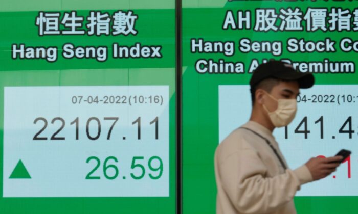 A man walks past a bank's electronic board showing the Hong Kong share index at Hong Kong Stock Exchange, on April 7, 2022. (Vincent Yu/AP Photo)
