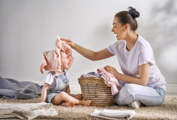 mother folding laundry and playing with her toddler