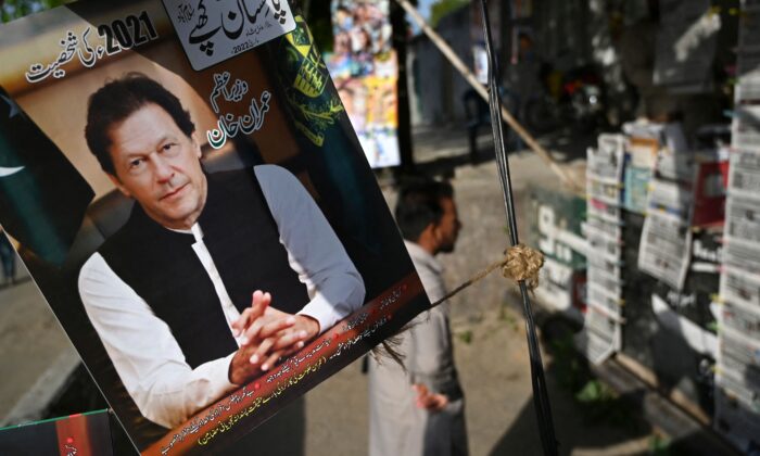 A resident stands beside a picture of Pakistan's Prime Minister Imran Khan as he looks at the morning newspapers displayed for sale at a roadside stall in Islamabad on April 4, 2022. (Aamir Qureshi/AFP via Getty Images)