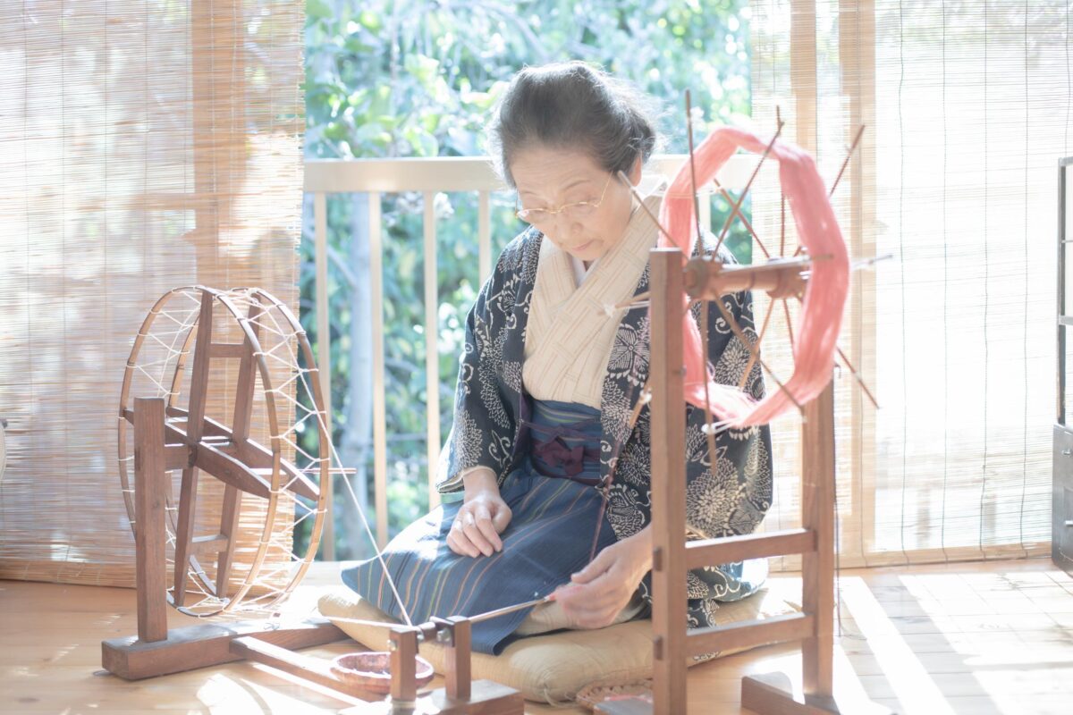 Japanese silk-weaver Sonoko Sasaki spins silk floss into yarn to make raw silk using the traditional tsumugi-ori weaving technique. “Sonoko Sasaki, from 'The Ateliers of Wonders Series, 2020,'” by photographer Rinko Kawauchi. (Rinko Kawauchi/Michelangelo Foundation) 