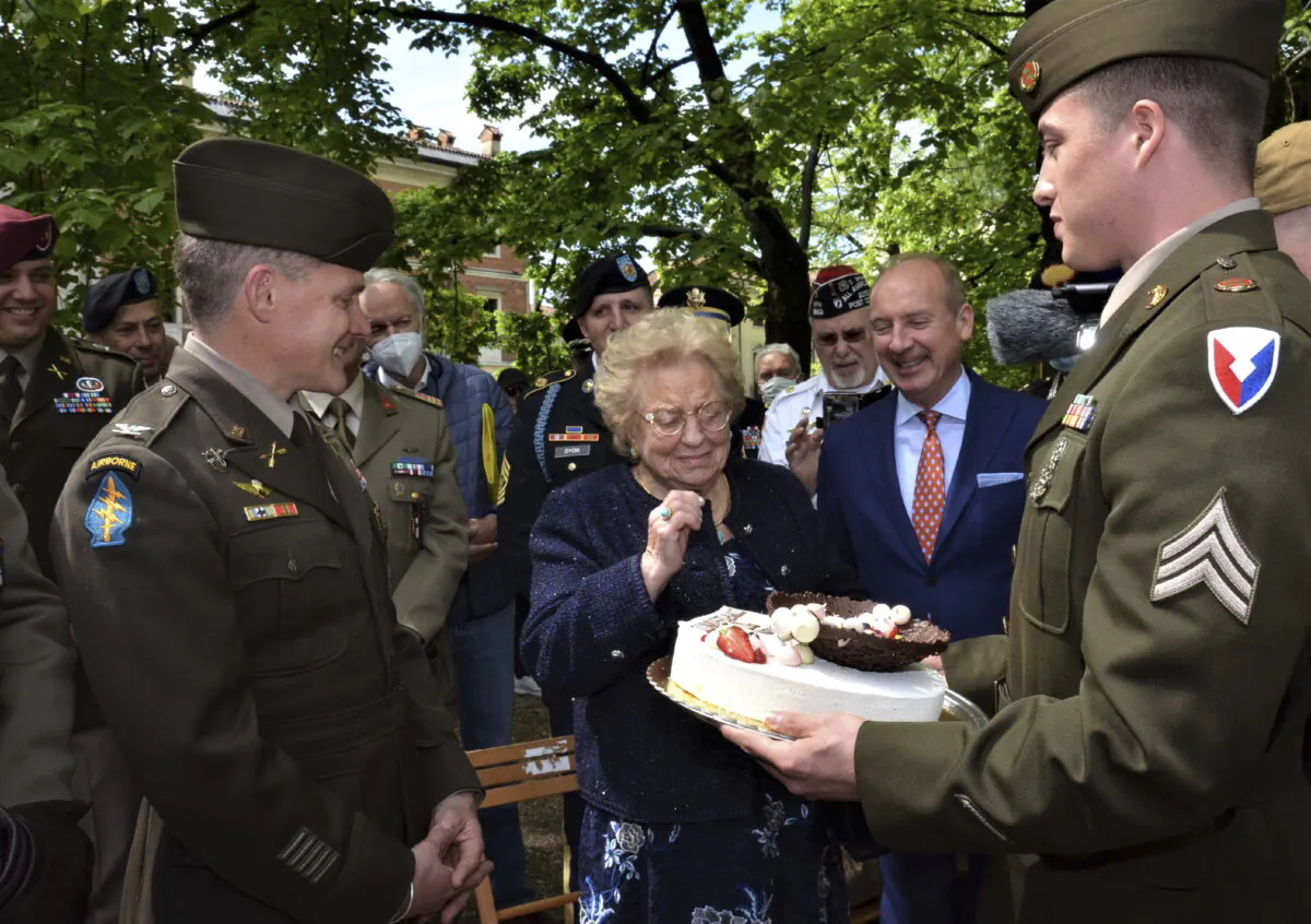 Soldiers from U.S. Army Garrison Italy return a birthday cake to Meri Mion (C) in Vicenza, northern Italy, on April 28, 2022. (Laura Krieder, U.S. Army via AP)