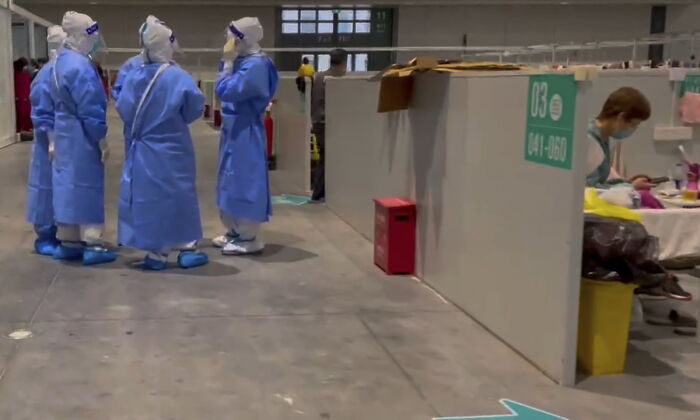 Medical workers chat at the National Exhibition and Convention Center in Shanghai on April 15, 2022.  (Beibei via AP)