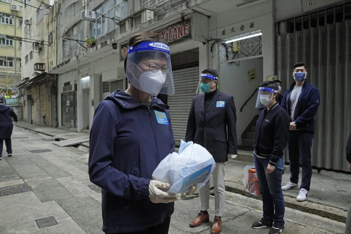 Hong Kong Chief Executive Carrie Lam, left, holds a package of COVID-19 prevention materials to be delivered to people during an anti-epidemic event in Hong Kong, on April 2, 2022. (Kin Cheung/AP Photo)
