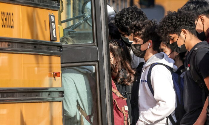 Students board a school bus outside of Washington-Liberty High School in Arlington County which is one of several school districts which sued to stop the mask-optional order by Governor Glenn Youngkin (R), in Arlington, Va., on Jan. 25, 2022. (Evelyn Hockstein/Reuters)