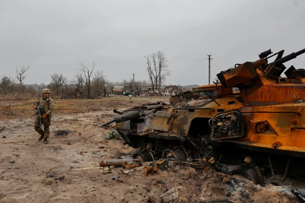 A Ukrainian service member inspects a destroyed Russian BTR-82 armored personal carrier (APC) in a village near a frontline as Russia's attack on Ukraine continues, in the Kyiv region, Ukraine, on March 31, 2022. (Serhii Nuzhnenko/Reuters)
