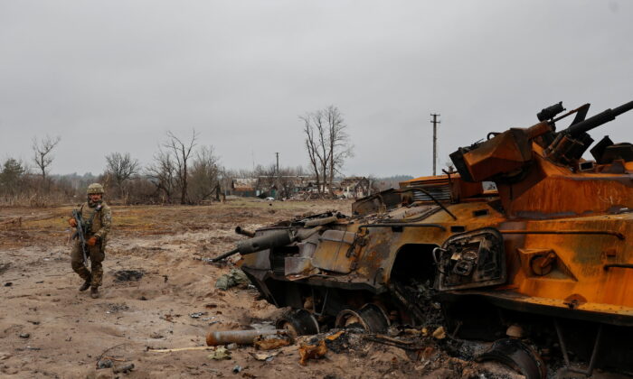 A Ukrainian service member inspects a destroyed Russian BTR-82 armored personal carrier (APC) in a village near a frontline as Russia's attack on Ukraine continues, in the Kyiv region, Ukraine, on March 31, 2022. (Serhii Nuzhnenko/Reuters)