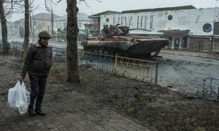 2022 年 4 月 1 日，在乌克兰基辅地区的马卡里夫镇，随着俄罗斯对乌克兰的袭击仍在继续，一名当地男子走过一辆受损的装甲运兵车。（Serhii Mykhalchuk/路透社）