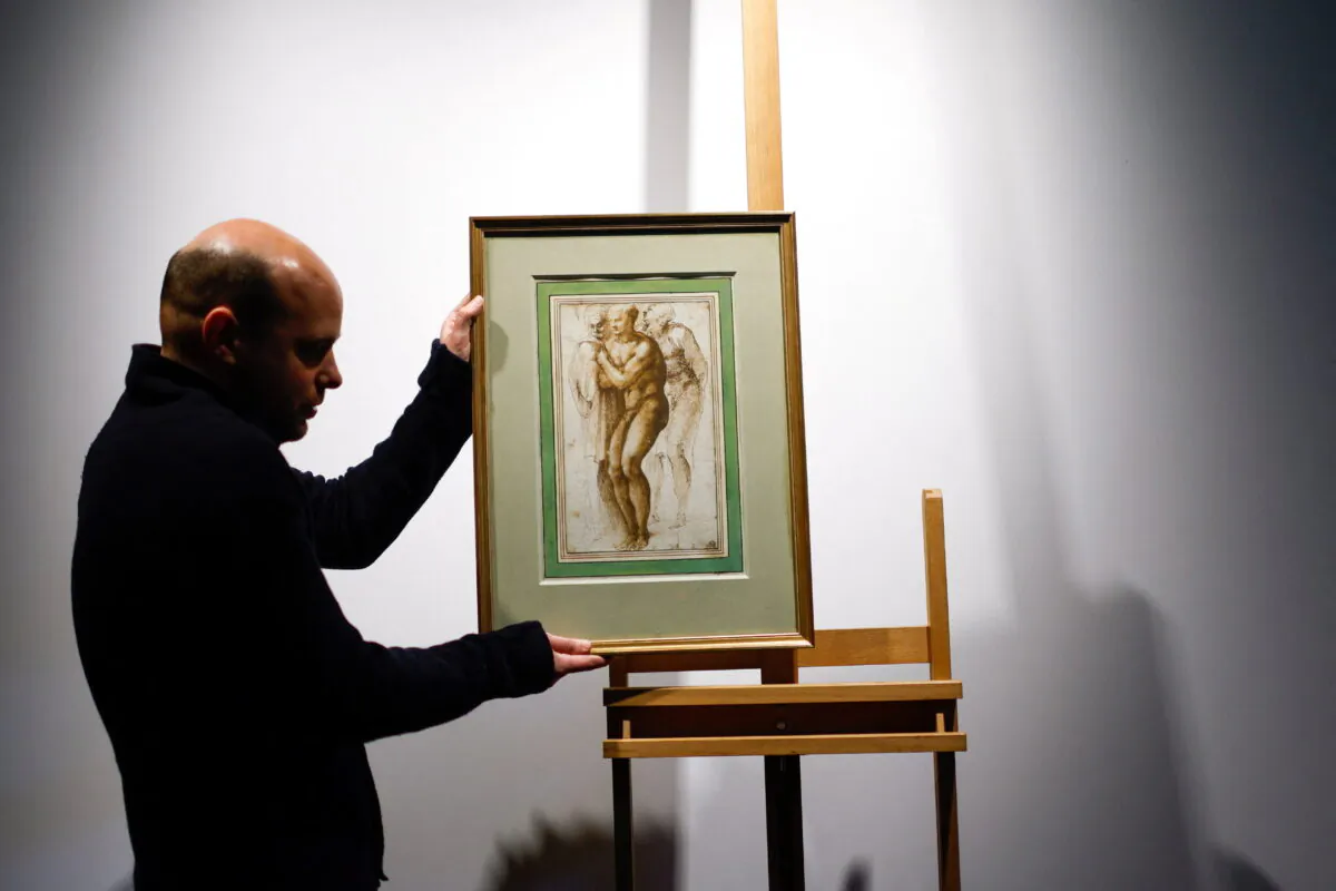 A Christie's employee installs the drawing "A nude young man (after Masaccio) surrounded by two figures" by Michelangelo Buonarroti (1475–1564) before its auction at Christie's auction house in Paris, on April 5, 2022. (Gonzalo Fuentes/Reuters)