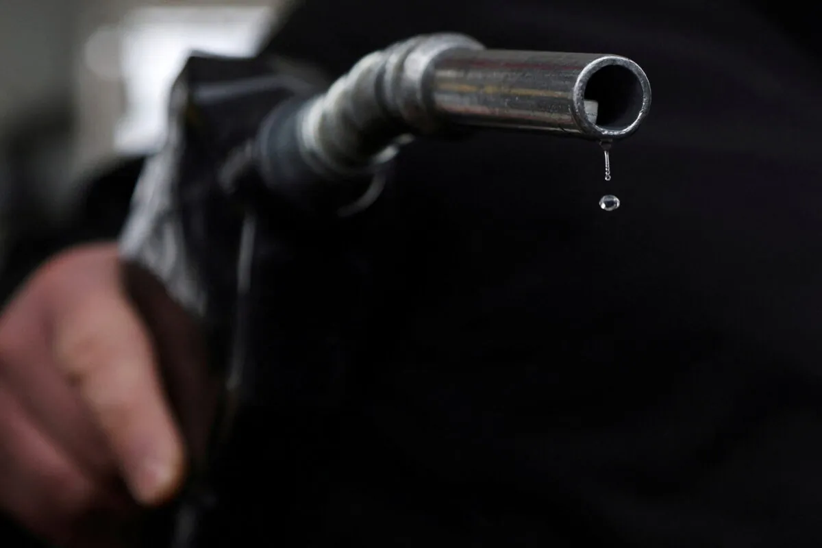 Gasoline drips out of a nozzle held by a gas station mechanic in Somerville, Massachusetts, on March 7, 2022. (Brian Snyder/Reuters)