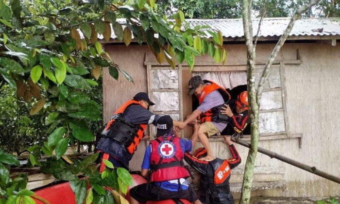 Rescue personnels assist a man onto a rescue boat after the tropical storm Megi hit, in Capiz Province, Philippines, on April 12, 2022. (Philippine Coast Guard/Handout via Reuters)