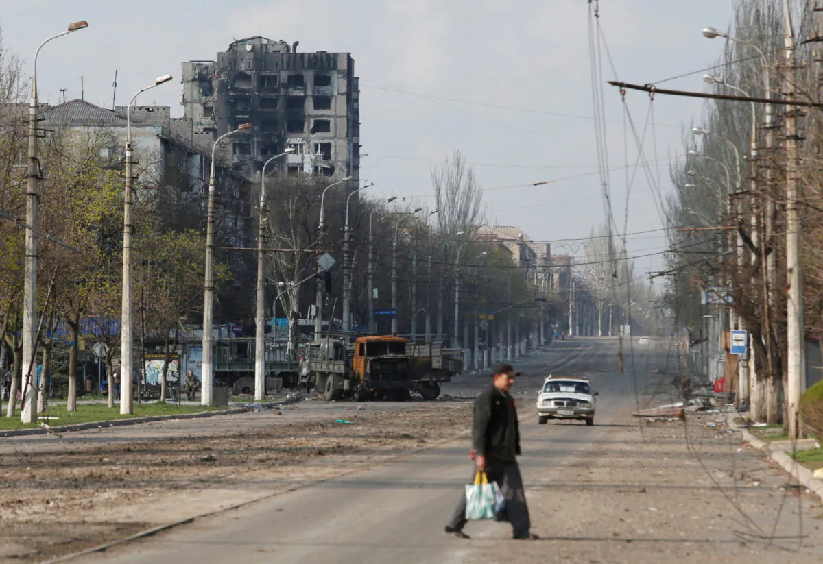 A local resident crosses a street damaged during Ukraine-Russia conflict in the southern port city of Mariupol, Ukraine April 15, 2022. (Reuters/Alexander Ermochenko