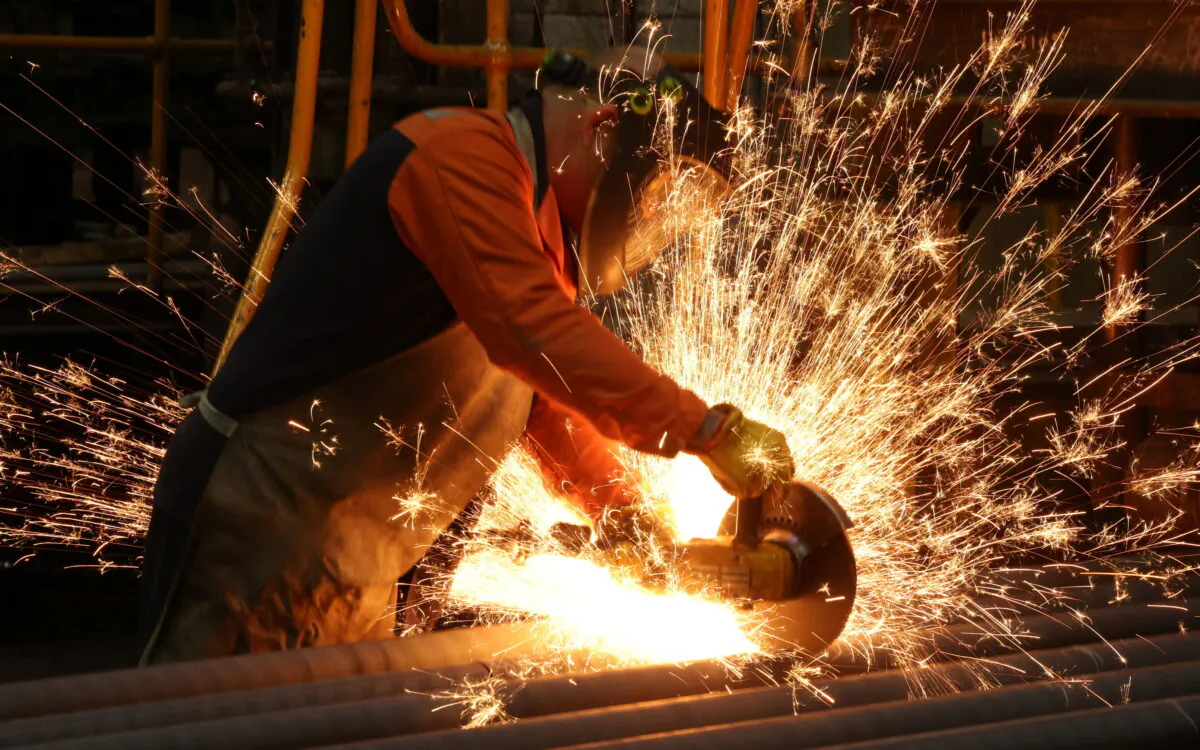 A worker cuts newly manufactured bars of steel at the United Cast Bar Group's foundry in Chesterfield, Britain, on April 12, 2022.  (Phil Noble/Reuters)